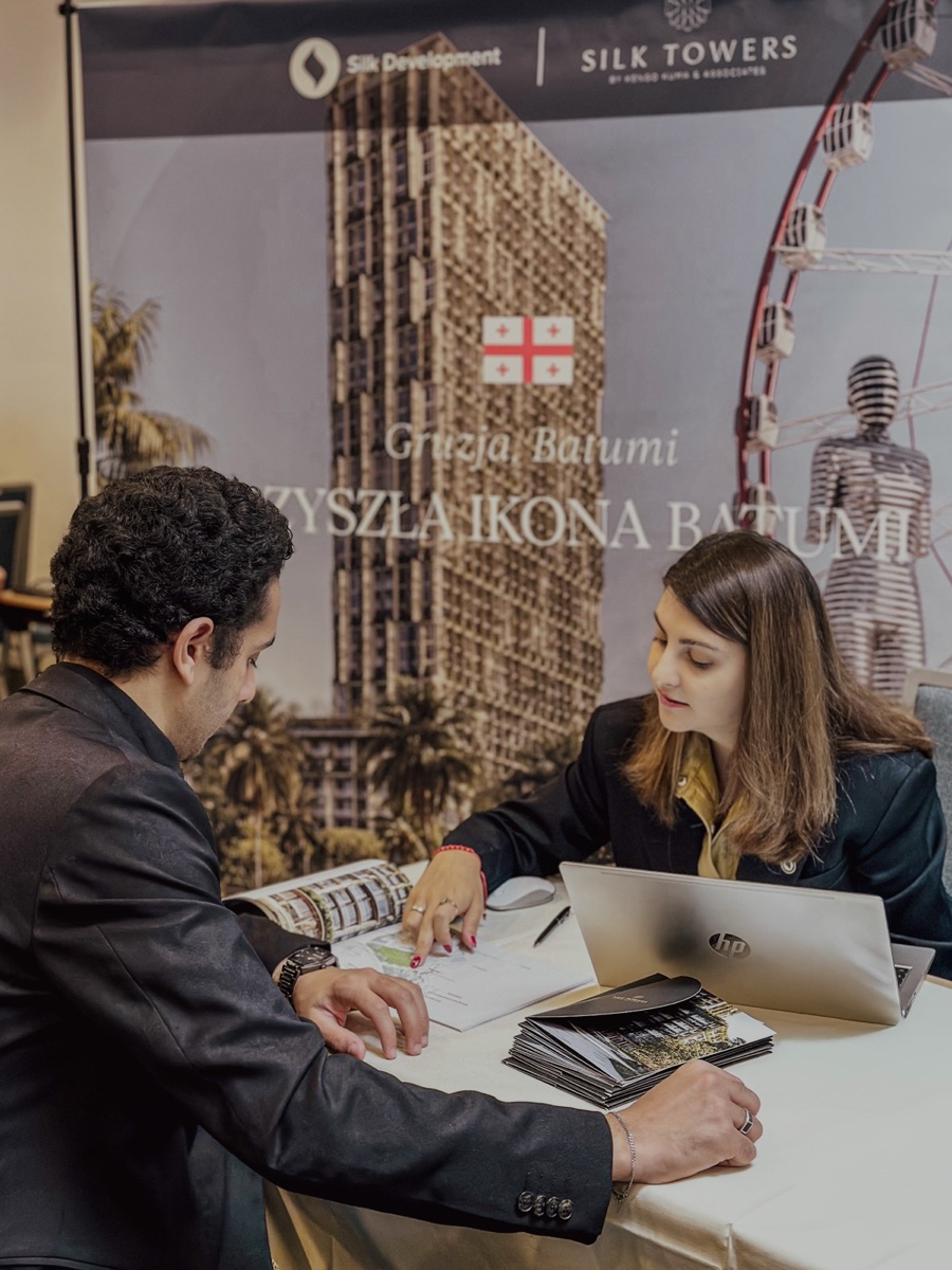 Two attendees in a meeting at the Silk Towers expo booth, with the Silk Development backdrop.